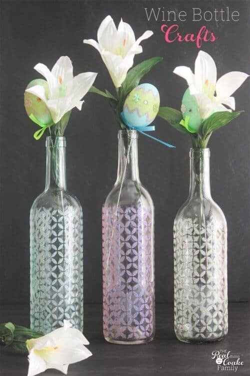 3 wine bottles made into vases with lily flowers in the vases
