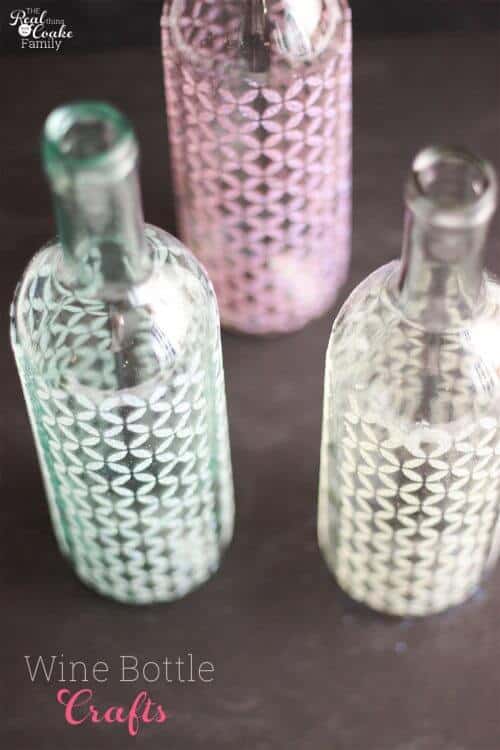 picture from above of 3 wine bottles stenciled with mod podge and glitter to make vases