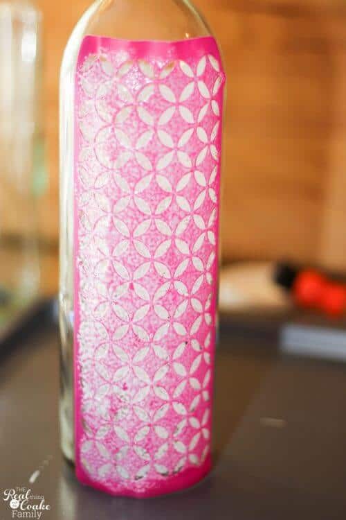 wine bottle with adhesive stencil on it covered with a layer of Mod Podge