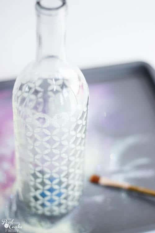 showing finished wine bottle craft with glitter and stenciled pattern