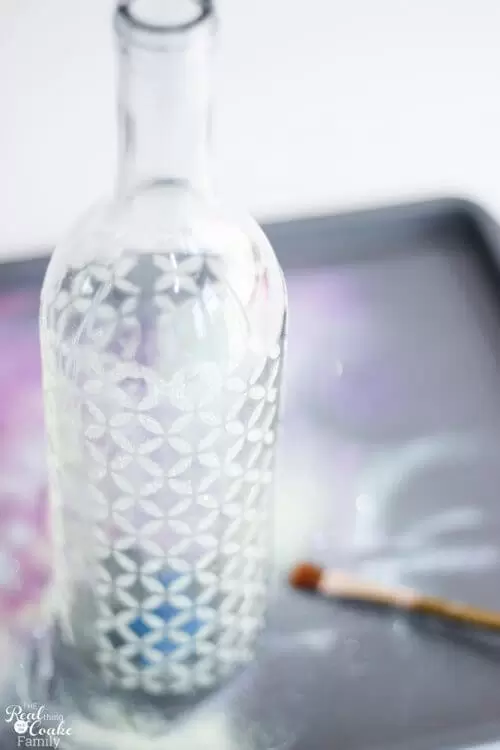 showing finished wine bottle craft with glitter and stenciled pattern