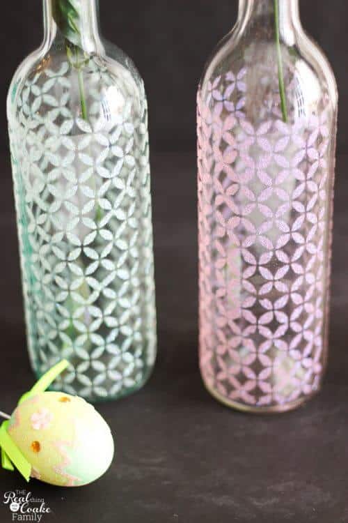 Showing 2 completed wine bottle crafts with glitter and stenciled pattern