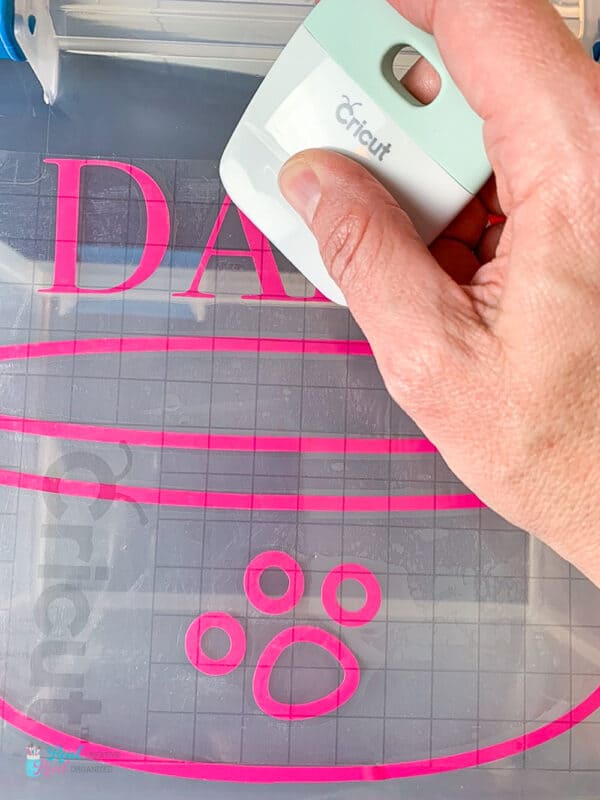 Using Cricut scraper to place and adhere vinyl to pet food storage bins
